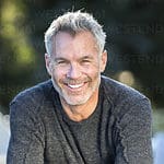 Portrait of gray-haired man smiling and leaning on outdoor table with crossed arms, Massachusetts, USA